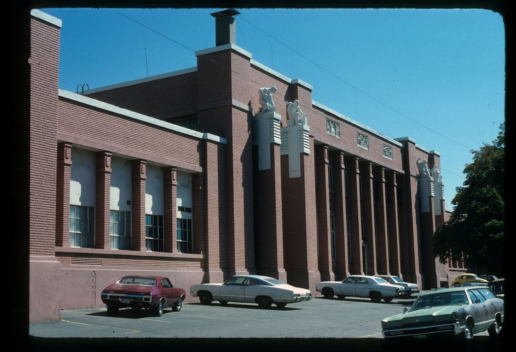 The west side of the Technical High School Building, photographed by the State Historic Preservation Office (SHPO) staff in 1978. The original yellow brick had been painted to match other buildings on the campus. Contrasting concrete caps on the columns and horizontal bands above and below the windows were obscured by paint, but the building still maintained its imposing Prairie-style presence.(State Historic Preservation Office photo, Utah State Archives, Series 30306.)