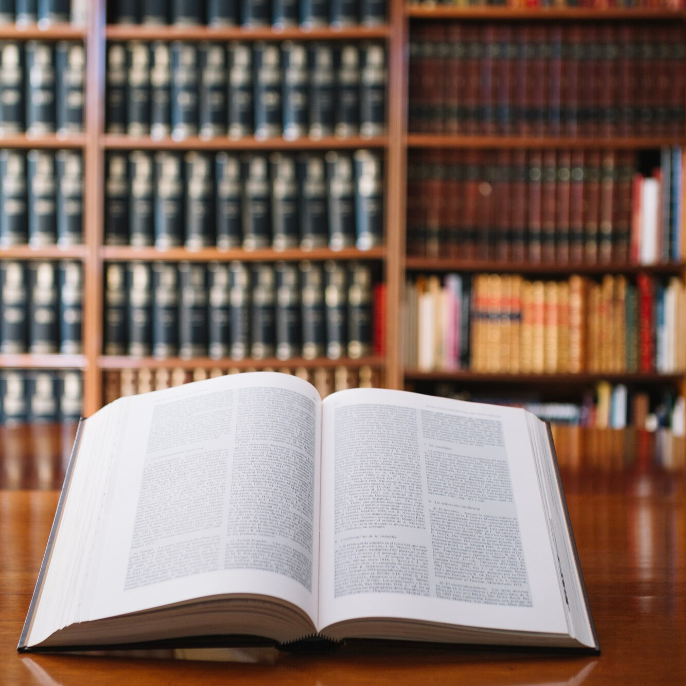 Open book on table in front of law bookshelf