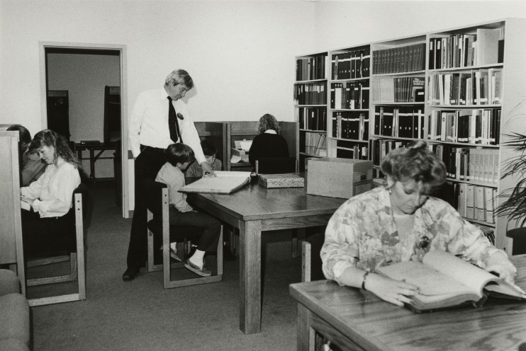 A black and white photo showing people researching at tables in the old Research Room.