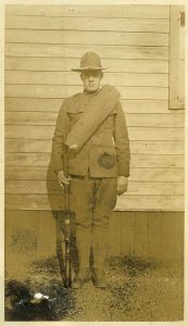 Delbert in uniform, standing at attention with his rifle at his side. 