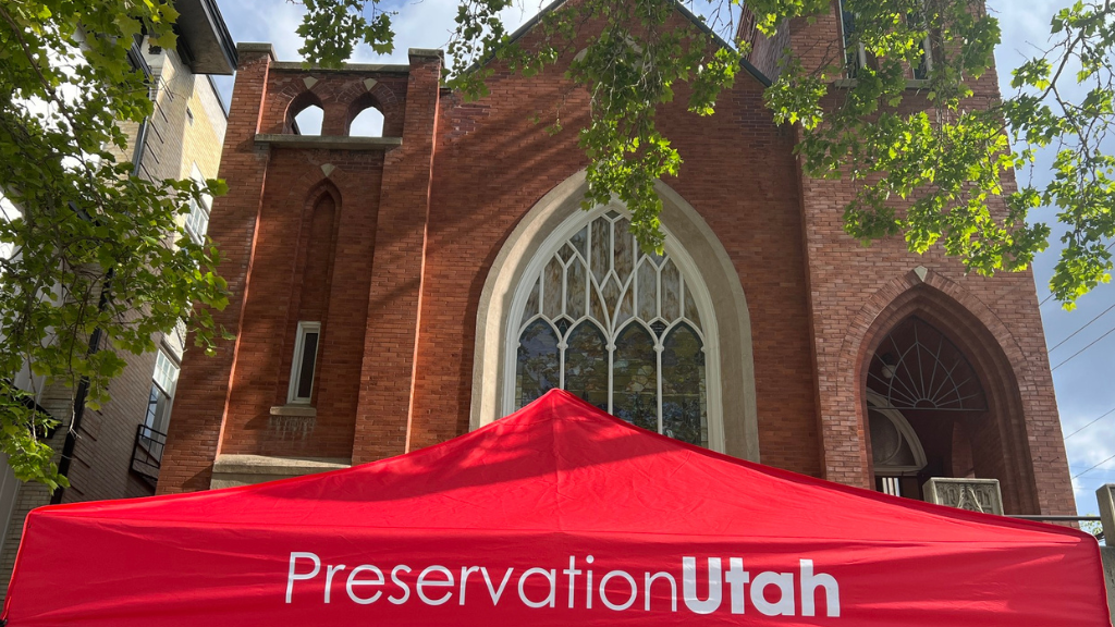 Photo of the Preservation Utah tabling tent in front of a brick building with trees.