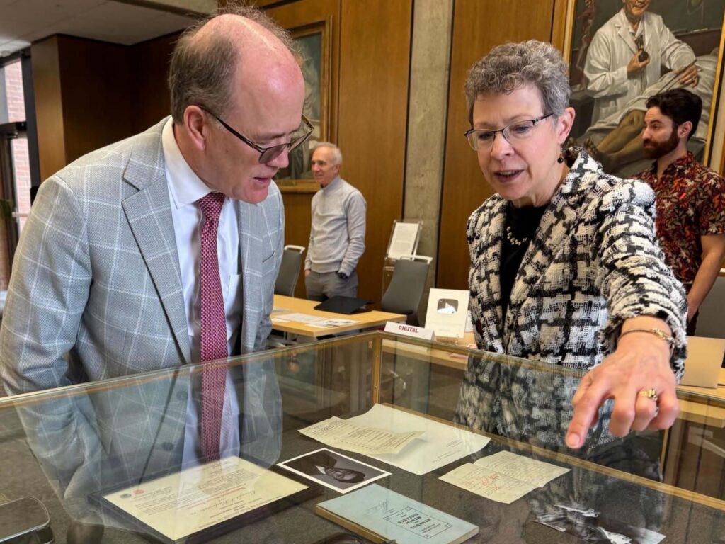 Executive Director of the Eccles Health Sciences Library, Catherine Soehner and Dr. Bob Carter, Senior Vice President for health sciences look into a glass case exhibit holding some of Dr. Hashimoto’s medical equipment. 