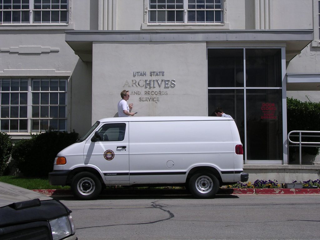 Alan Barnett behind a white van taking down the Utah State Archives sign at the old building.