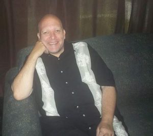 Jim Duke sitting on a couch smiling