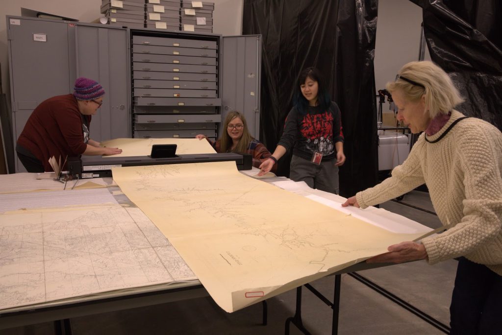 From the left: Emma Fox, Katie Saunders, Jamie Nakano, and Anne Lawlor carefully scan an oversized map from NHMU’s Archaeological Map Collection.