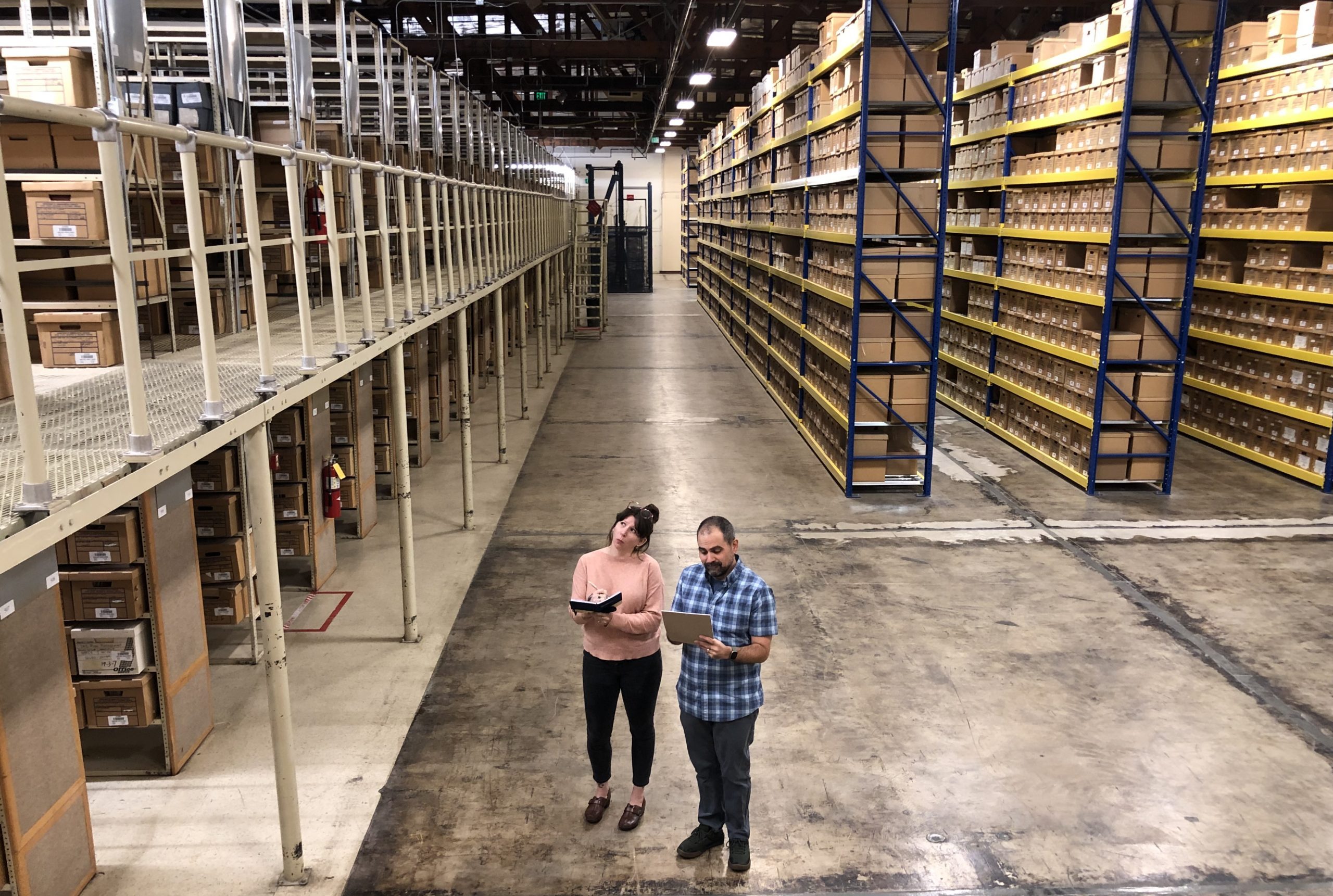 Jim and Melissa standing in the foreground of a massive warehouse filled with records!