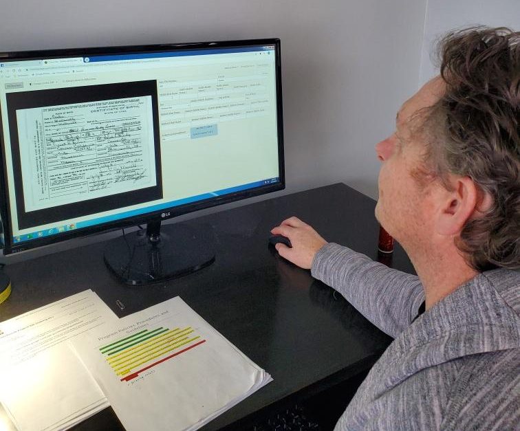 A volunteer works on transcribing a document using his computer.
