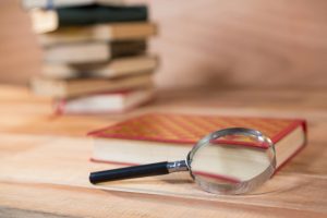 Magnifying glass with a book on a wooden table